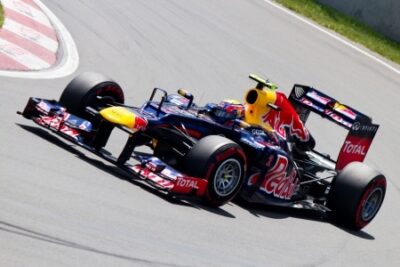 A race car emblazoned with Red Bull and Total logos speeds along a track, capturing a dynamic moment in the Canadian Grand Prix history.