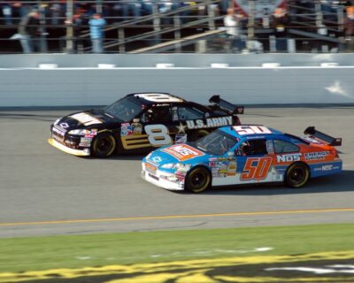 Two race cars, one numbered 8 and the other 50, speed side-by-side during a Daytona 500 race.