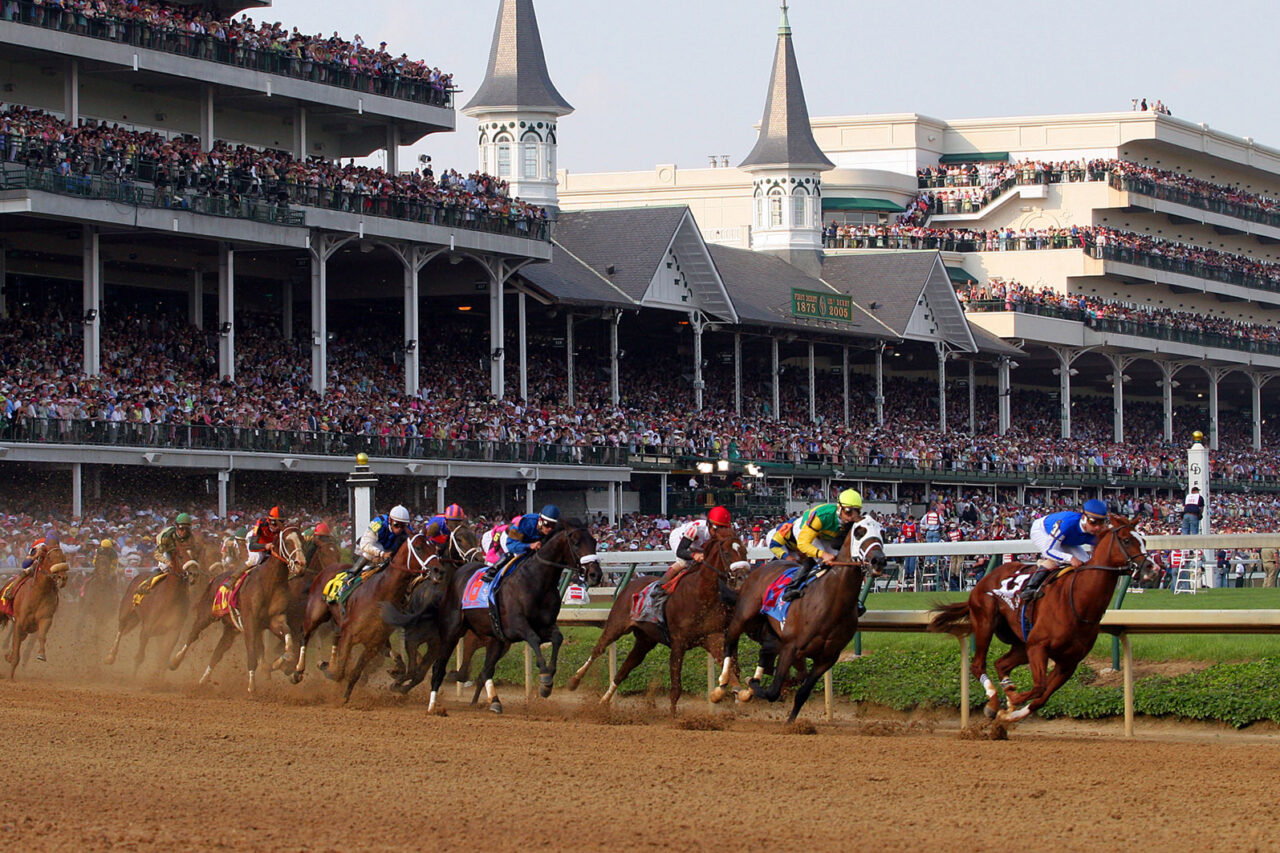 Horses race on a dirt track in front of a packed grandstand at the Kentucky Derby, showcasing the event's excitement and tradition.