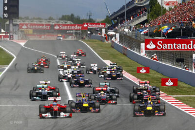 Formula 1 race cars speed down the track with a crowd watching, highlighting a top F1 sports event attended by Roadtrips guests.