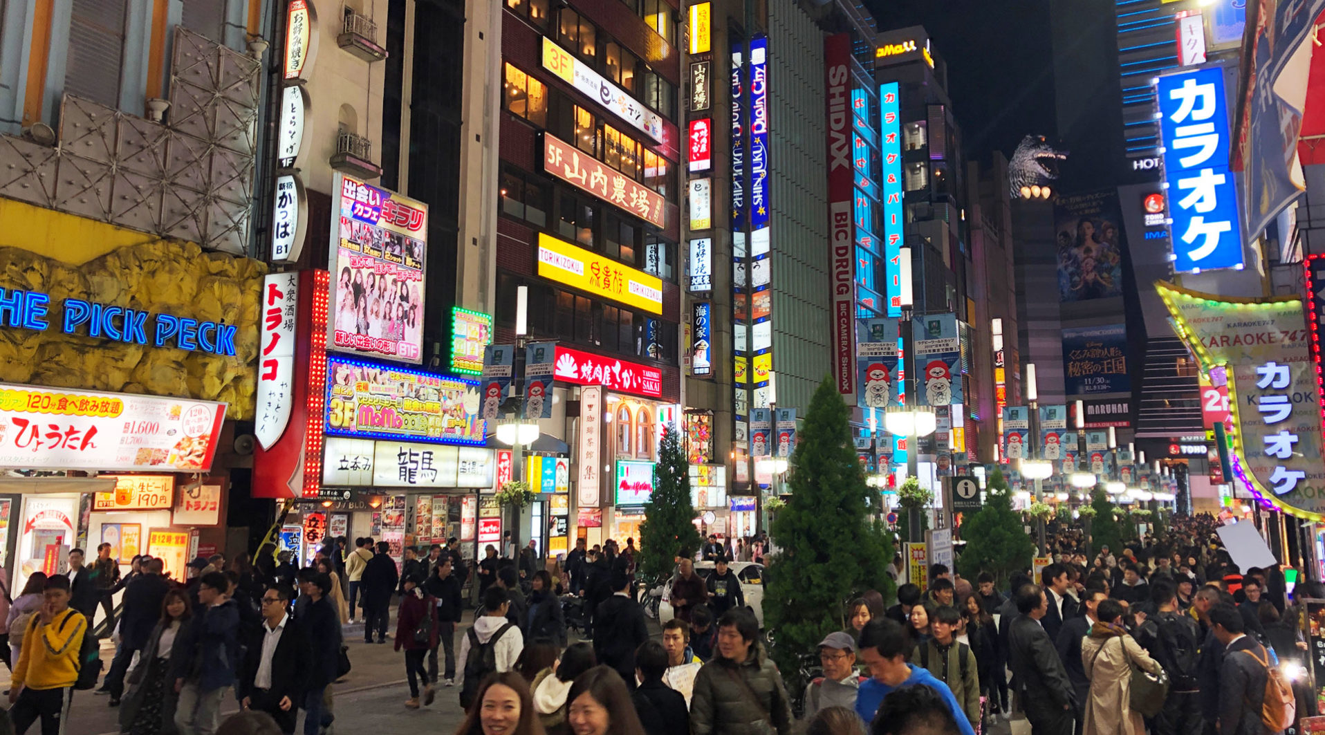 Crowded Tokyo street at night, illuminated by numerous colorful signs and billboards, with many people walking, best for visiting during the Summer Games.