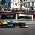 A Formula 1 race car speeds past a crowded viewing area in Monaco, capturing the excitement of the Las Vegas Grand Prix event.