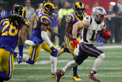 Football player in white uniform evading opponents during a Super Bowl game, highlighting must-see sporting events for the ultimate sports enthusiast.