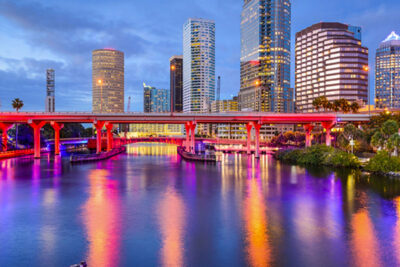 Downtown Tampa skyline at twilight with illuminated bridges reflecting in the water, highlighting attractions for Super Bowl weekend.