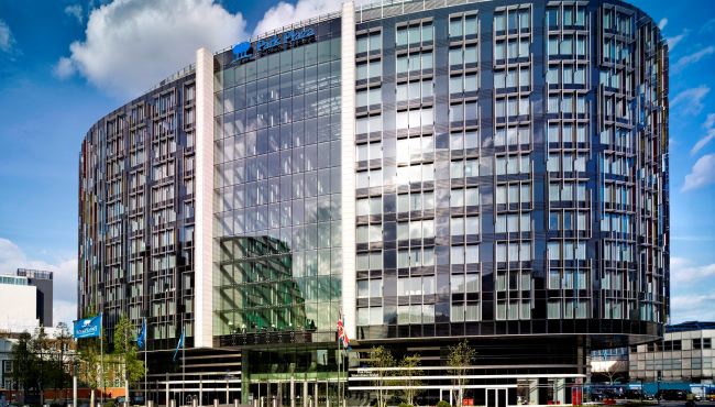 Modern exterior view of the Park Plaza Westminster Bridge Hotel in London, England, showing its glass facade and circular design, ideal for Wimbledon accommodations.
