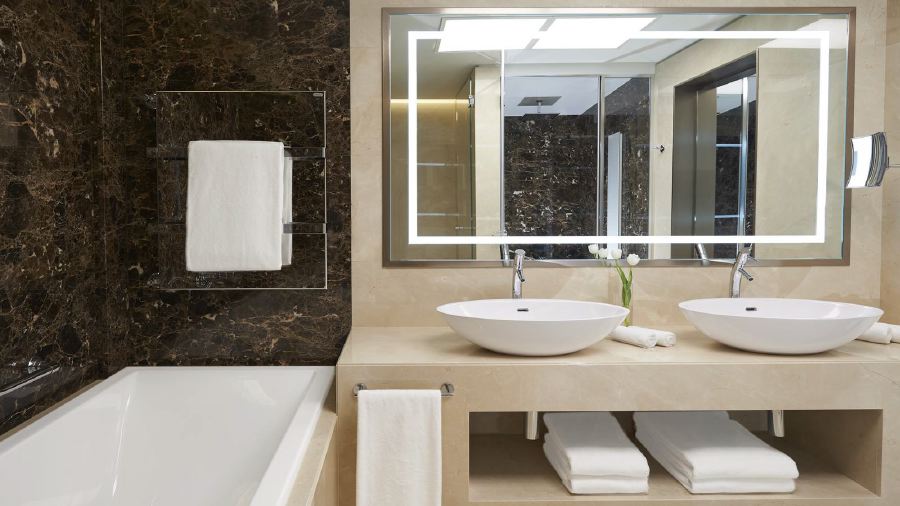 Elegant bathroom at the Excelsior Hotel Gallia in Milan, featuring double vessel sinks, a large mirror, and marble surfaces, ideal for Italian Grand Prix attendees seeking luxury accommodations.