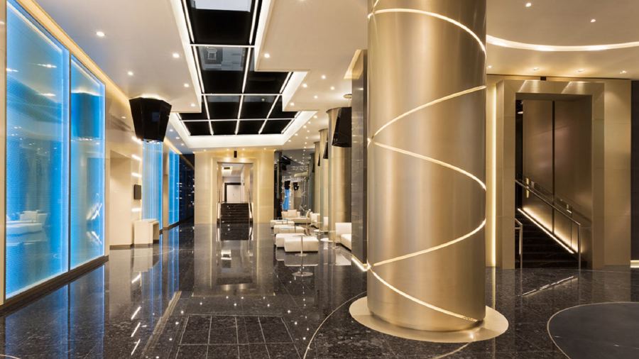 Luxurious interior of the Excelsior Hotel Gallia in Milan, featuring sleek, modern design with blue illuminated walls, golden accents, and a reflective marble floor.