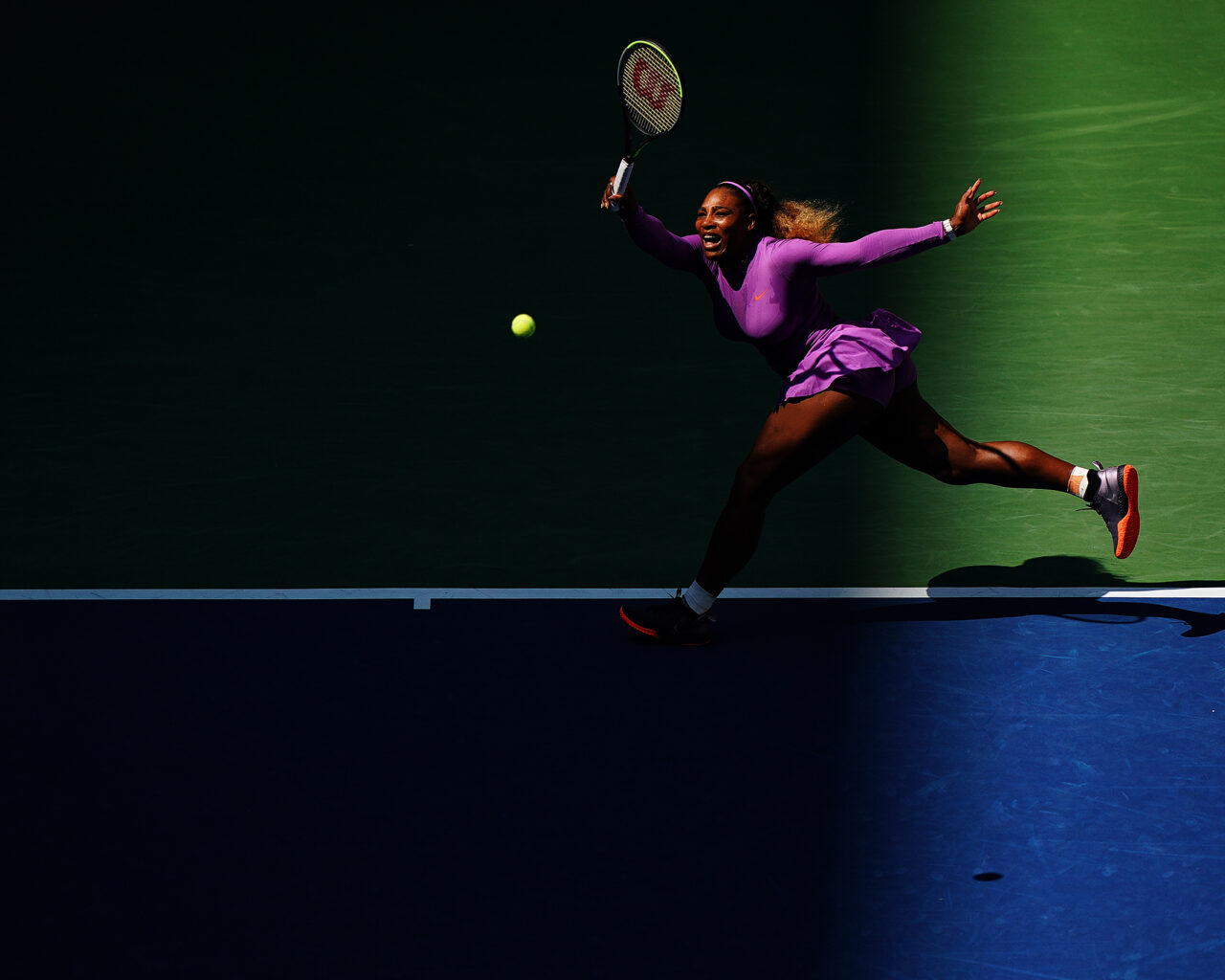 Tennis player lunges to strike a ball during a US Open match, emphasizing the dynamic action and competition of the US Open Tennis Packages.