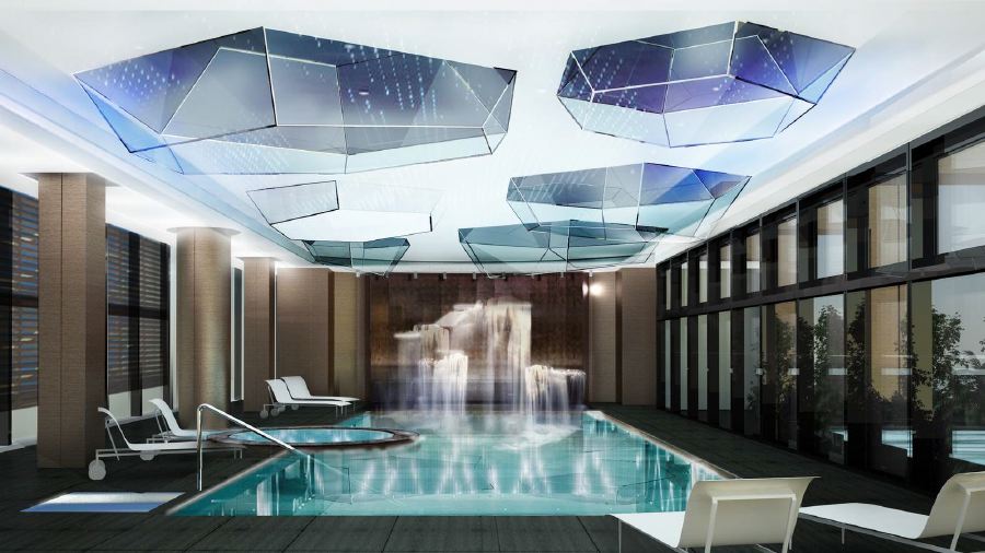 Modern indoor pool area at the Excelsior Hotel Gallia in Milan, featuring unique overhead lighting, lounge chairs, and a decorative fountain, ideal for visitors of the Italian Grand Prix.