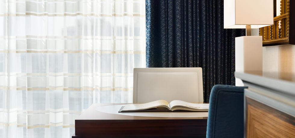 Elegant hotel room in Austin, Texas, featuring a desk with an open book, a laptop, and sleek modern furnishings, ideal for attendees of the US Grand Prix.
