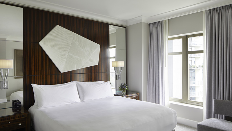 Elegant king-size bed in a deluxe Waldorf Astoria Atlanta Buckhead room, ideal for World Cup Hotels & Accommodations in Atlanta, featuring modern lighting and stylish interior.