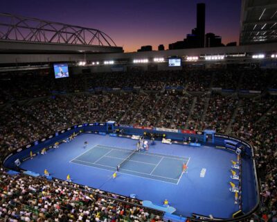 Twilight sets over a bustling Australian Open tennis match, showcasing players in action with a packed stadium audience, ideal for exploring sports travel packages.