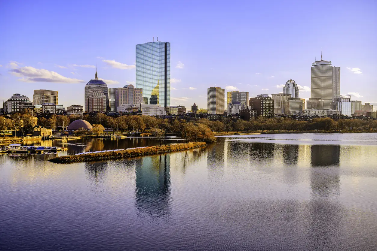 View of the Boston skyline featuring modern buildings and a calm river, highlighting Boston's role as a World Cup city with a venue at Gillette Stadium which seats 70,000.