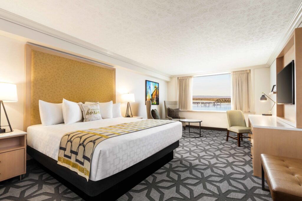 King-sized bed with patterned blankets in a spacious room at The Galt House Hotel, overlooking a bridge, ideal for Kentucky Derby accommodations in Louisville.