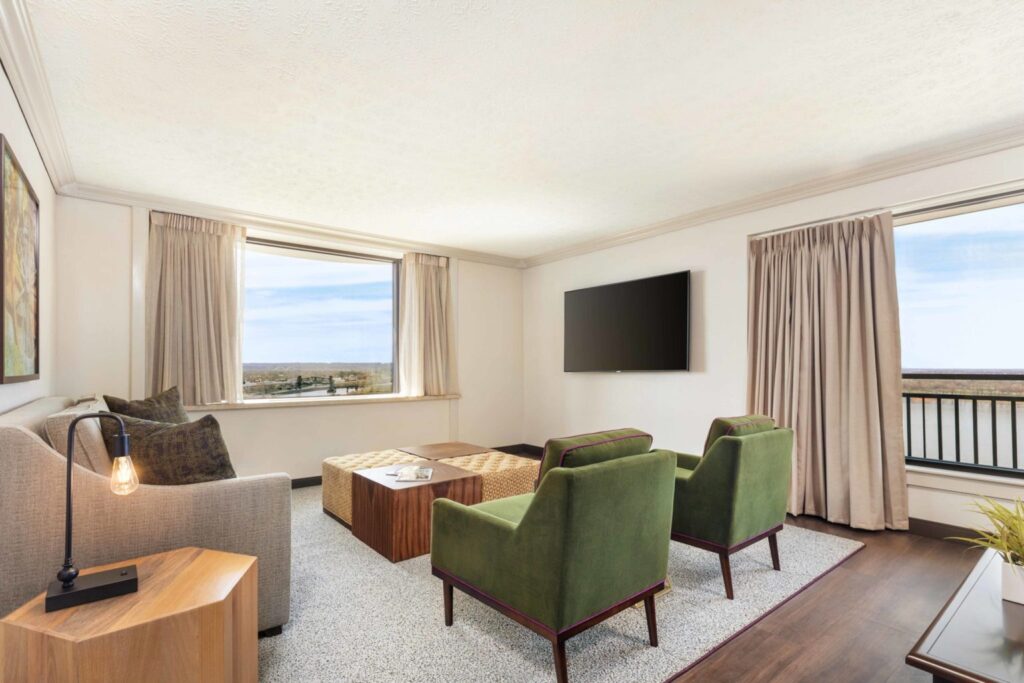 Bright and spacious parlor suite at Galt House Hotel featuring modern furniture, large windows with outside views, ideal for guests visiting Louisville for the Kentucky Derby.