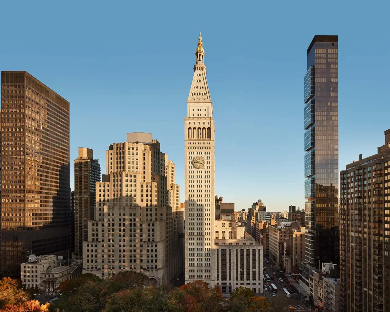 Aerial view of a bustling cityscape with a prominent clock tower surrounded by modern skyscrapers during fall, highlighting an urban setting relevant for luxury travel to major events.