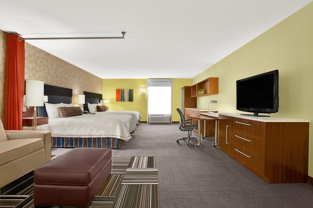 Bright and modern double queen studio suite at Hilton Home2 Suites in Augusta, Georgia, featuring two beds, a desk area, and a cozy sitting section, ideal for Augusta accommodations.