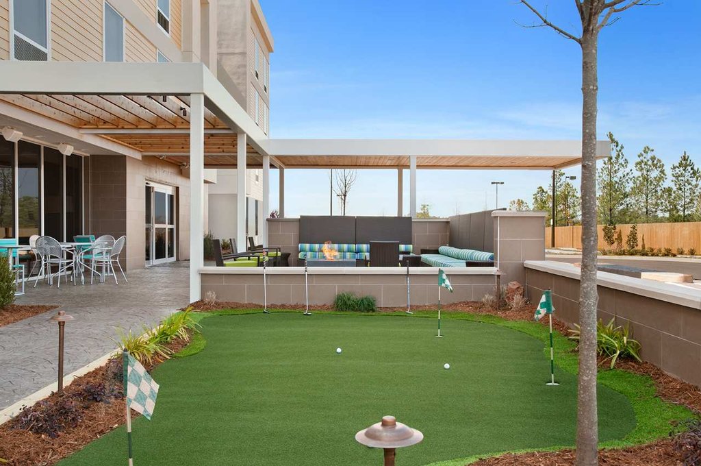 Mini golf area with seating and dining facilities at Home2 Suites by Hilton in Augusta, Georgia, ideal for visitors seeking accommodations near Augusta's golf attractions.