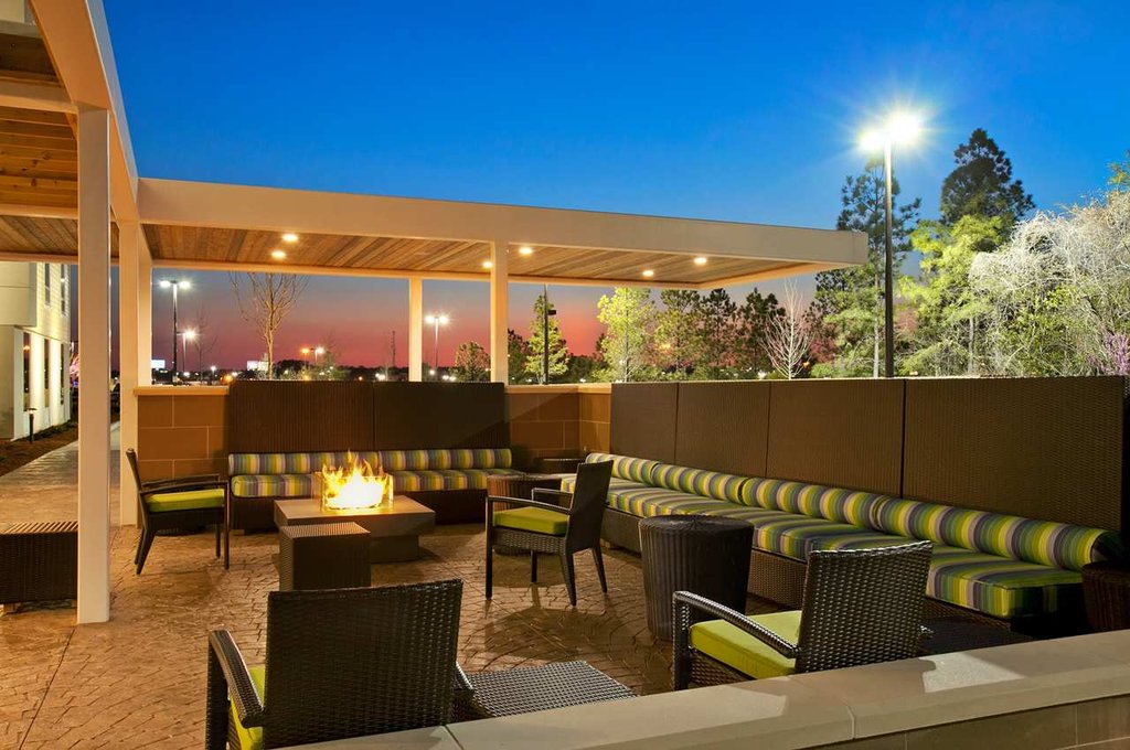 Outdoor patio area at Hilton Home2 Suites in Augusta, Georgia, featuring modern seating arrangements, a fire pit, under a twilight sky, ideal for visitors looking for Augusta hotels and accommodations.