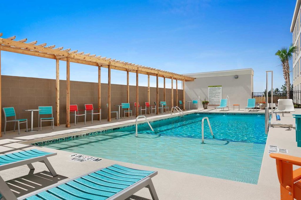 Outdoor pool area at Hilton Home2 Suites in Augusta, showcasing lounge chairs and a pergola, ideal for guests visiting Masters Augusta Hotels.