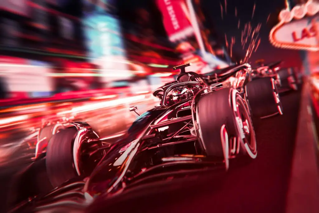 Race cars speed down a track at the Las Vegas Grand Prix, highlighted by vibrant, blurred lights and racing imagery perfect for those seeking Las Vegas Grand Prix Packages.