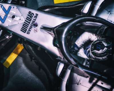 Close-up view of a Formula 1 race car and driver in the cockpit, showcasing the detailed engineering and branding of a high-performance vehicle.