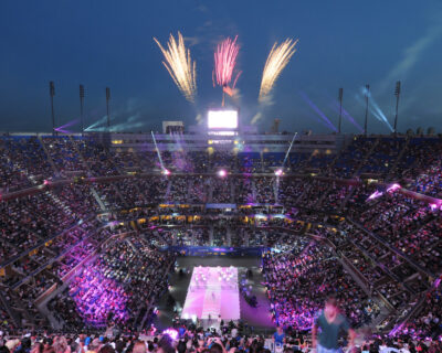 Fireworks light up the night sky above a packed stadium during the opening ceremony of a US Open Tennis event, showcasing the custom US Open Tennis Packages available.