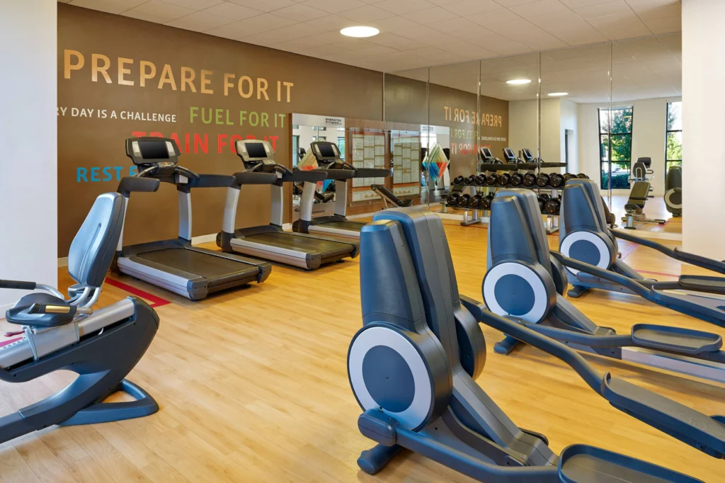 Well-equipped fitness center at Sheraton Augusta Hotel featuring treadmills, ellipticals, and weights, ideal for guests looking to stay fit while visiting Augusta for the Masters.