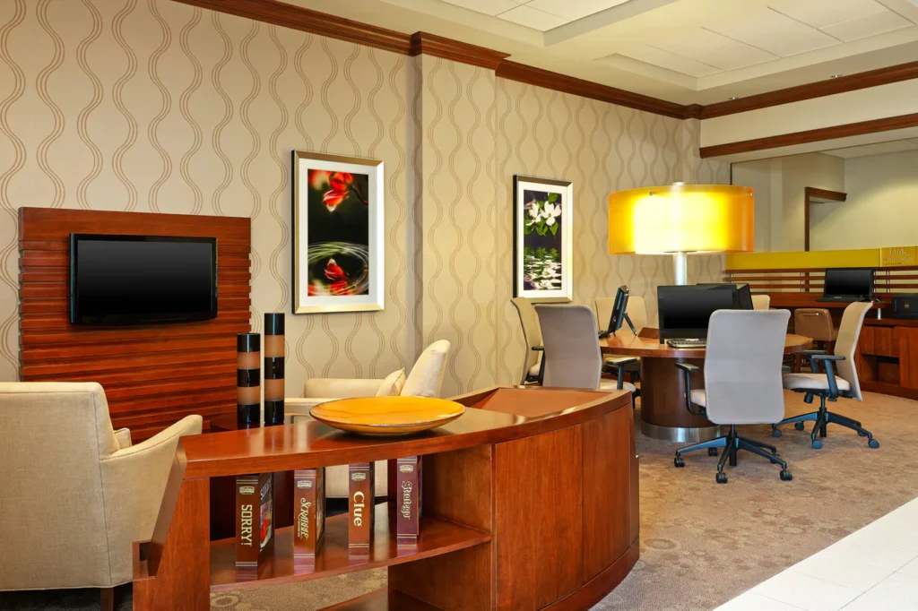 Elegant lobby area of the Sheraton Augusta Hotel, featuring a well-equipped business center with contemporary furniture, ambient lighting, and artistic decor, ideal for guests visiting Augusta, GA for the Masters.