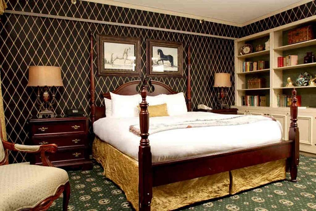 Elegant bedroom at The Brown Hotel in Louisville, Kentucky, featuring a four-poster bed and sophisticated decor, ideal for guests attending the Kentucky Derby.