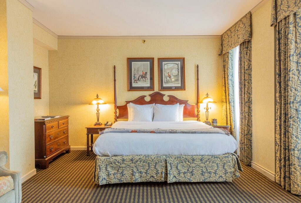 Luxury hotel room with elegant decor at The Brown Hotel in Louisville, Kentucky, featuring a large bed, classic furniture, and rich draperies; ideal for guests visiting the Kentucky Derby.