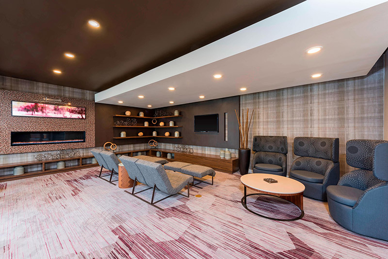 Modern lounge area at the Courtyard by Marriott in downtown Louisville, featuring a fireplace, plush seating, and vibrant decor, ideal for guests looking for luxury hotels near Churchill Downs.
