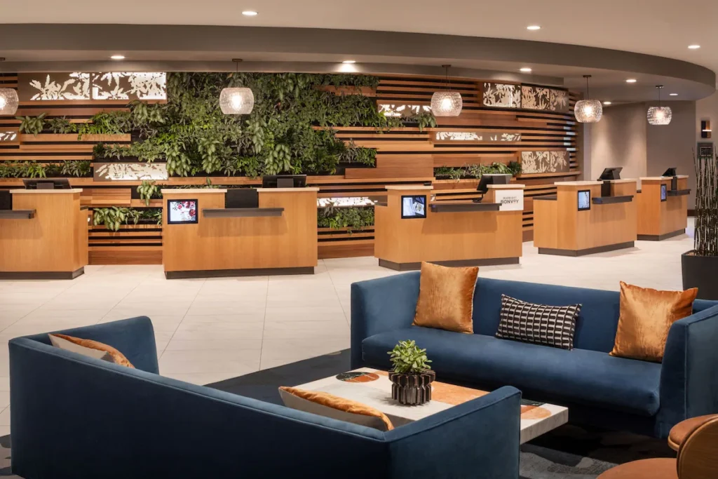 Elegant lobby area of the Westin Las Vegas Hotel & Spa, showcasing plush blue sofas and a distinctive green wall behind wooden reception desks, ideal for guests visiting Las Vegas or attending the Las Vegas Grand Prix.