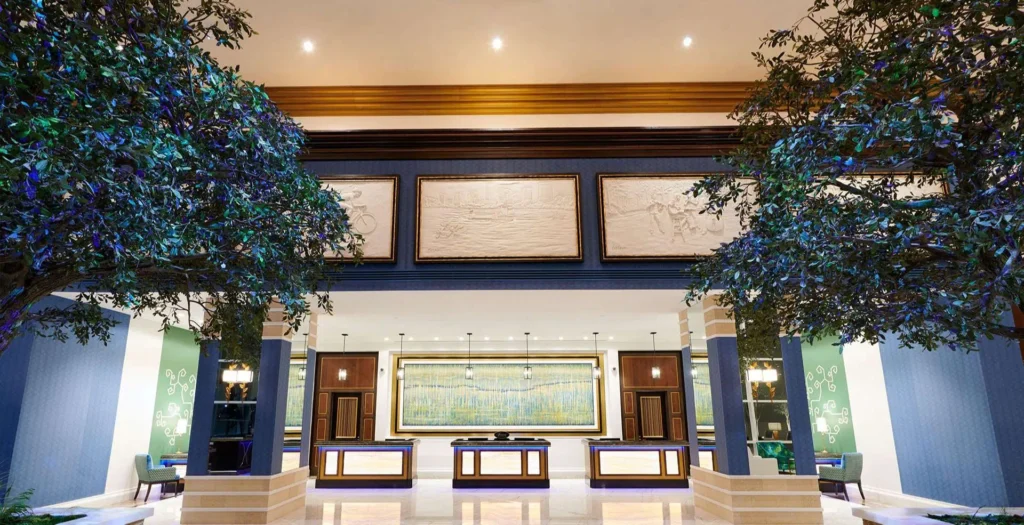 Interior of the Fairmont Austin Hotel lobby featuring elegant decor, including decorative bas-relief panels, lush indoor trees, and modern check-in desks under warm lighting.