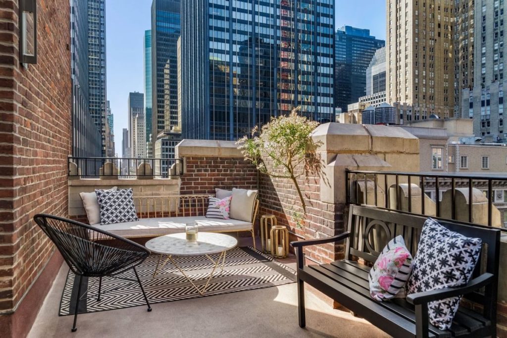 Luxury hotel terrace in New York featuring modern furniture with a backdrop of towering skyscrapers, near the Lexington Hotel, ideal for US Open Tennis visitors.