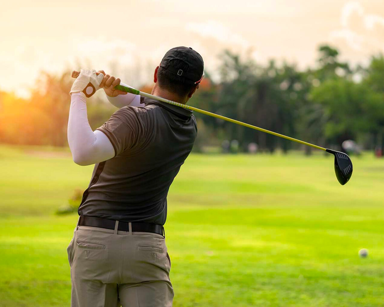 A golfer in action, swinging a driver on a sunny day, captures the essence of the premier golf event, the Masters Tournament in Augusta, GA.