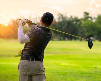 A golfer in action, swinging a driver on a sunny day, captures the essence of the premier golf event, the Masters Tournament in Augusta, GA.