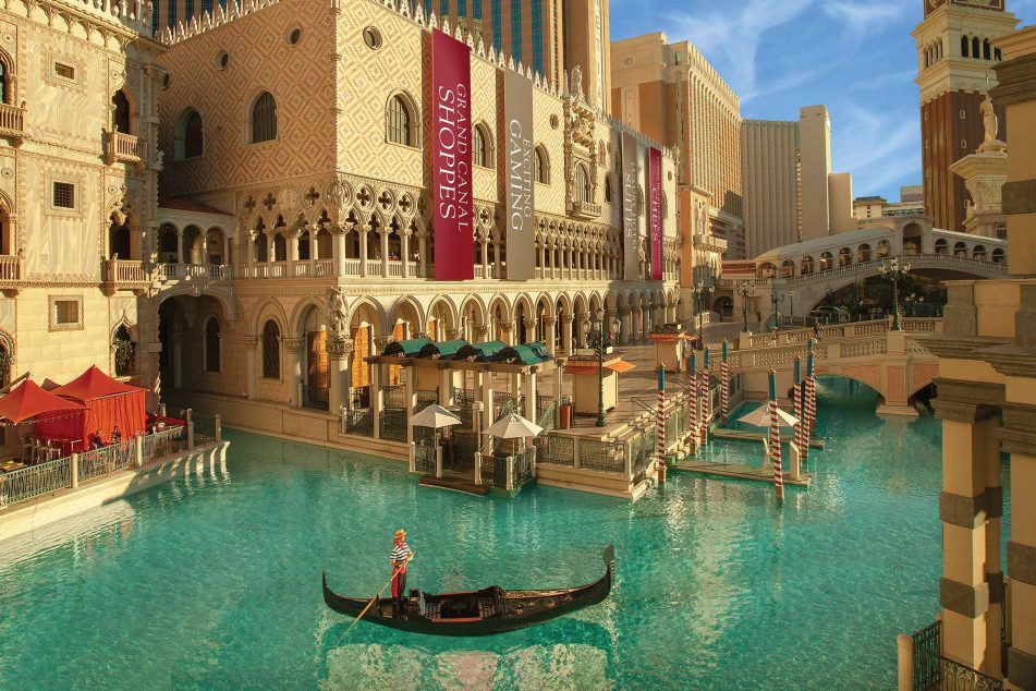 Gondola glides through Venetian-style canals outside The Venetian Resort in Las Vegas, surrounded by grand architecture and inviting shops, a popular choice for Las Vegas Grand Prix accommodations.