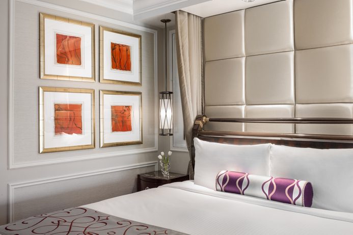 Luxurious hotel room at The Venetian Resort in Las Vegas, featuring a plush headboard, elegant bedding, framed art on the walls, and tasteful decor, ideal for Grand Prix attendees.