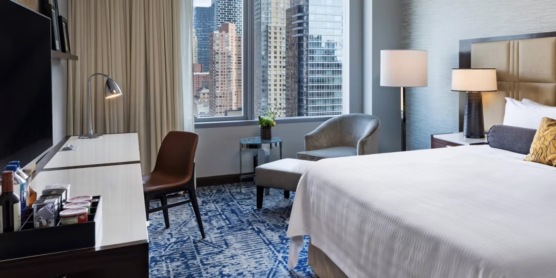 Luxury hotel room at InterContinental New York Times Square, featuring a large bed, city views, a workspace, and modern amenities, ideal for Ryder Cup accommodations.