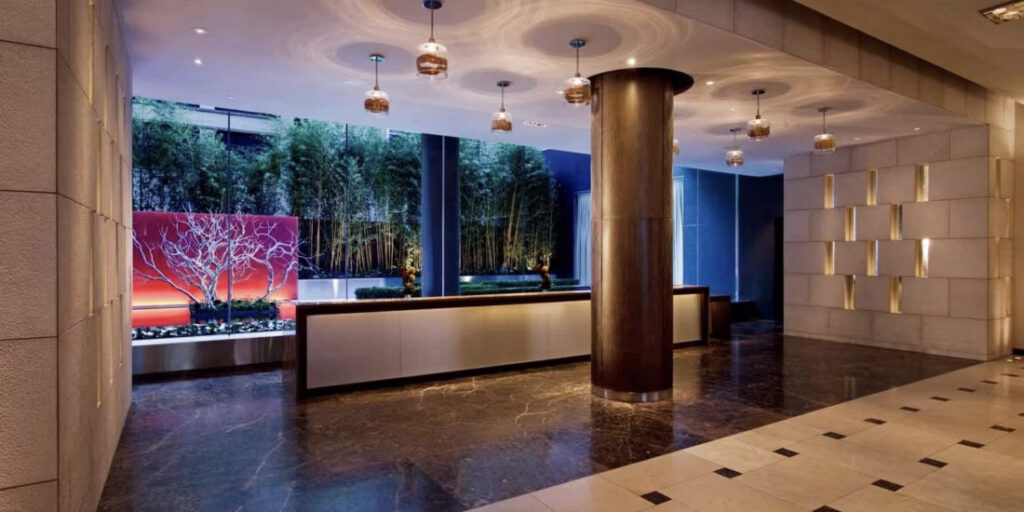 Lobby of the InterContinental New York Times Square, showcasing modern decor with artistic wall panels and mood lighting, ideal for those seeking luxury Ryder Cup accommodations in New York.