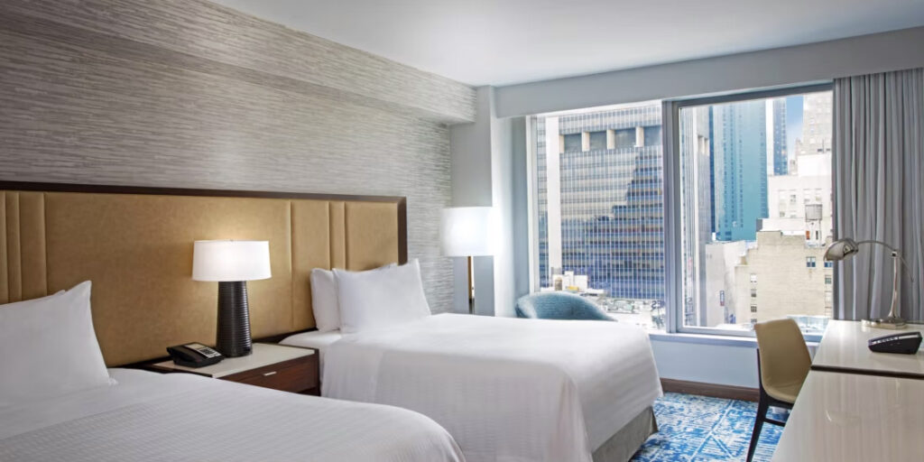 Luxury hotel room at the InterContinental New York Times Square, featuring two beds, modern decor, and a city view, ideal for visitors seeking accommodations near Ryder Cup venues.