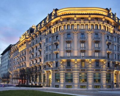 An opulent, illuminated hotel building captured at dusk, representing the luxury accommodations featured in the Italian Grand Prix travel packages.
