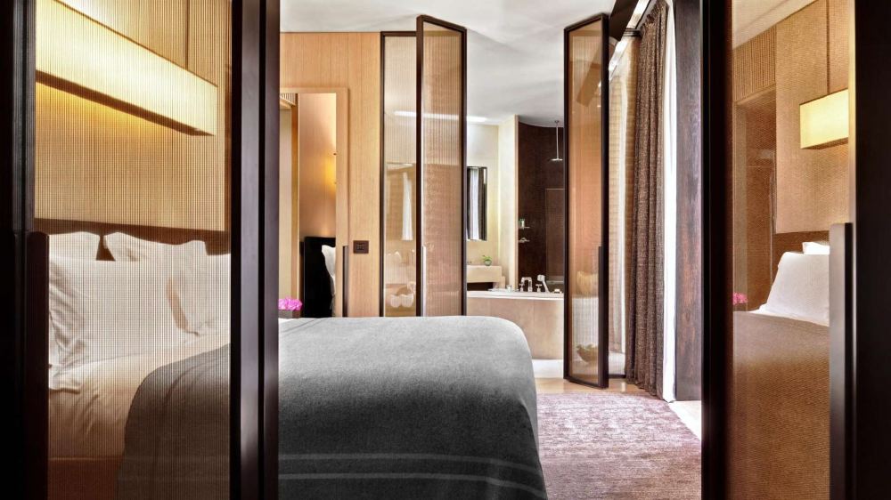 Luxurious hotel room featuring a modern design with wood paneling and neutral tones, located at Bvlgari Hotel Milano close to events like the Italian Grand Prix in Milan.