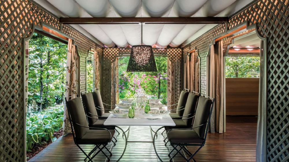 Elegant outdoor dining area at Bvlgari Hotel Milano, featuring a table set for a meal, surrounded by lush greenery and trellis walls, ideal for guests visiting Milan for the Italian Grand Prix.