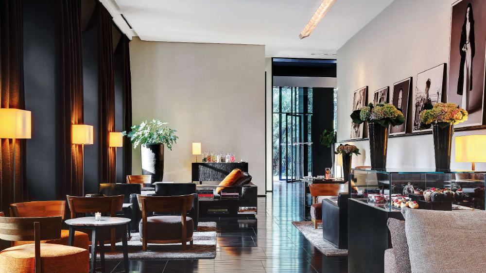Luxury hotel lobby in Milan with modern furnishings, artistic photographs on the walls, and elegant lighting, ideal for guests attending the Italian Grand Prix.