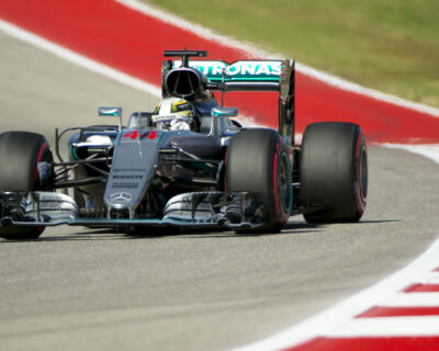 A Formula One race car, marked with the number 44 and Mercedes branding, speeds on a racetrack, emphasizing the excitement of US Grand Prix luxury travel packages.