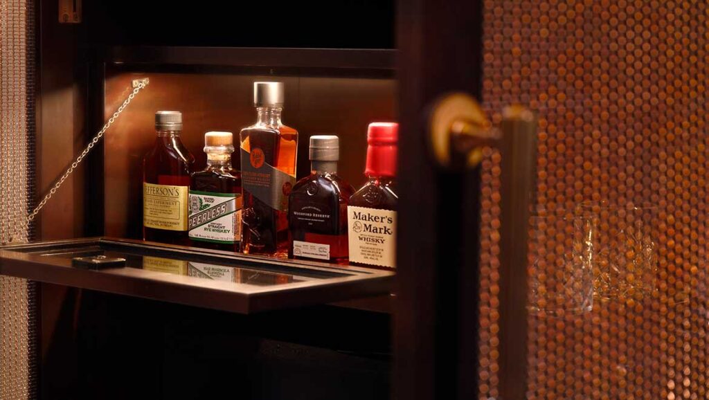 Luxury bourbon bar setup in a guest room at Omni Louisville, showcasing premium bottles, reflecting the comfort and elegance ideal for visitors attending the Kentucky Derby near Churchill Downs.