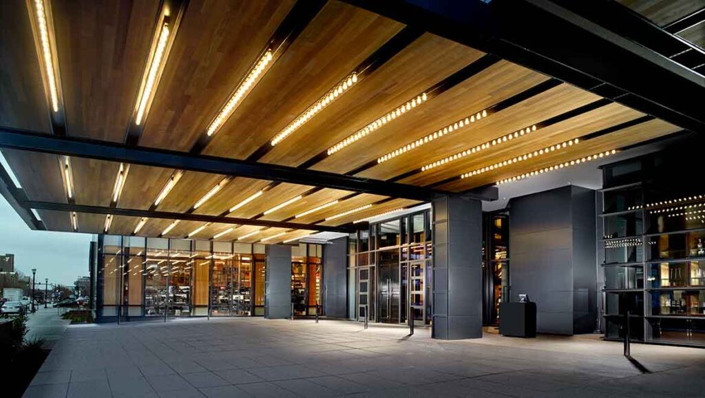 Modern luxury hotel entrance at 400 South 2nd Street in Louisville, Kentucky, featuring striking wooden underlit beams, ideal accommodation for Kentucky Derby enthusiasts near Churchill Downs.