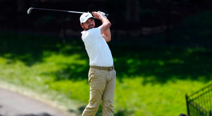 A golfer in white shirt and beige pants swings his club during a practice round at the Masters Golf Tournament in Augusta.